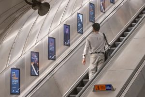 A man travelling up the escalators on The London Underground looking at the adverts for the UniteToProtect charity campaign.