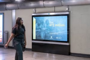 A photo capturing a passerby on the London Underground as she looks at the charity advert on the wall.